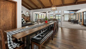 A spacious dining area with a long wooden table, benches, and a high ceiling with exposed beams. - Grand Lakefront Escape - Lakefront Cabin | Hot Tub, Pool Table (Big Bear Lake)