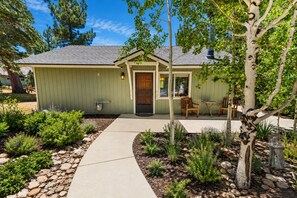 A single-story house with a front porch, a small garden with various plants and a pathway leading to the entrance.