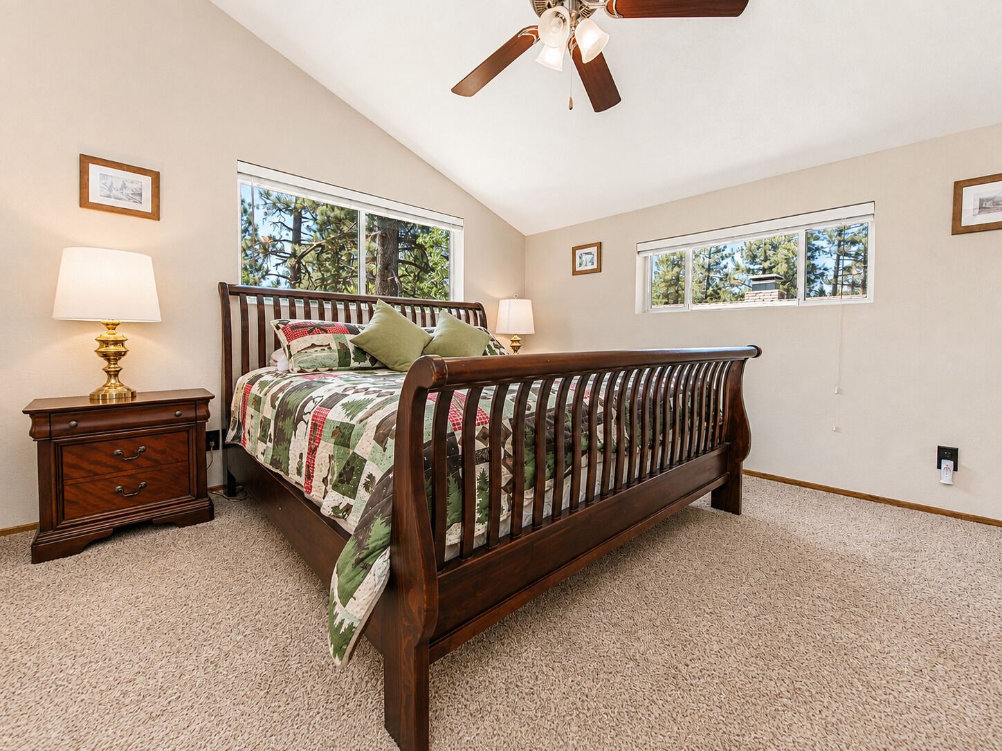 A bedroom with a wooden bed, two bedside lamps, a nightstand, and a ceiling fan.