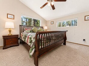 A bedroom with a wooden bed, two bedside lamps, a nightstand, and a ceiling fan.
