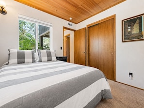 A bedroom with a large bed, a wooden door, and a window.