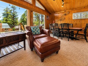 Una habitación acogedora con un sofá de cuero, una mesa de comedor con sillas y vistas al exterior.