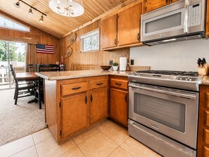 A kitchen with wooden cabinets, a stainless steel stove, and a microwave. - Cub Run Cabin -6 Bedroom, Walk to Lake/Village, Hot Tub, Foosball (Big Bear Lake)