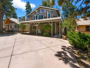 A two-story house with a balcony, a front porch, and a bear statue. - Cub Run Cabin -6 Bedroom, Walk to Lake/Village, Hot Tub, Foosball (Big Bear Lake)