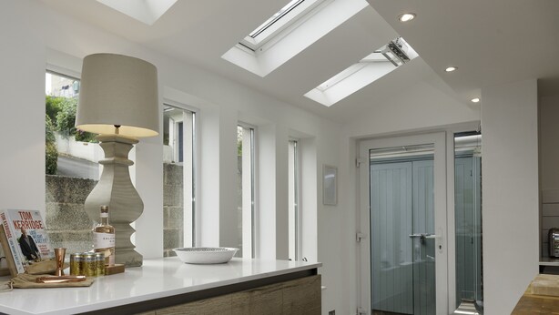 A modern kitchen with a large island, skylights, and a glass shower enclosure.