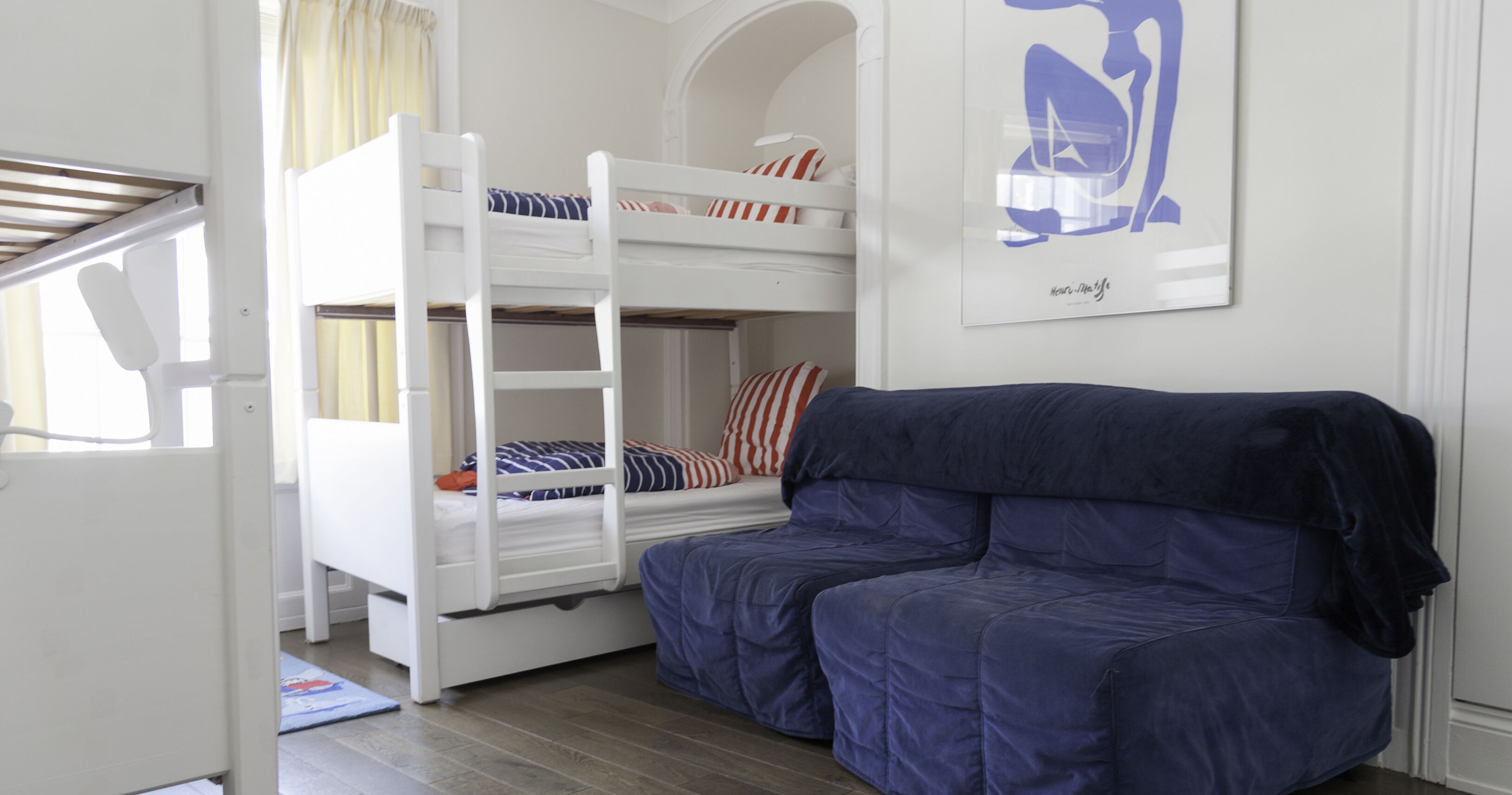 A bunk bed room with a blue sofa and a framed artwork on the wall.