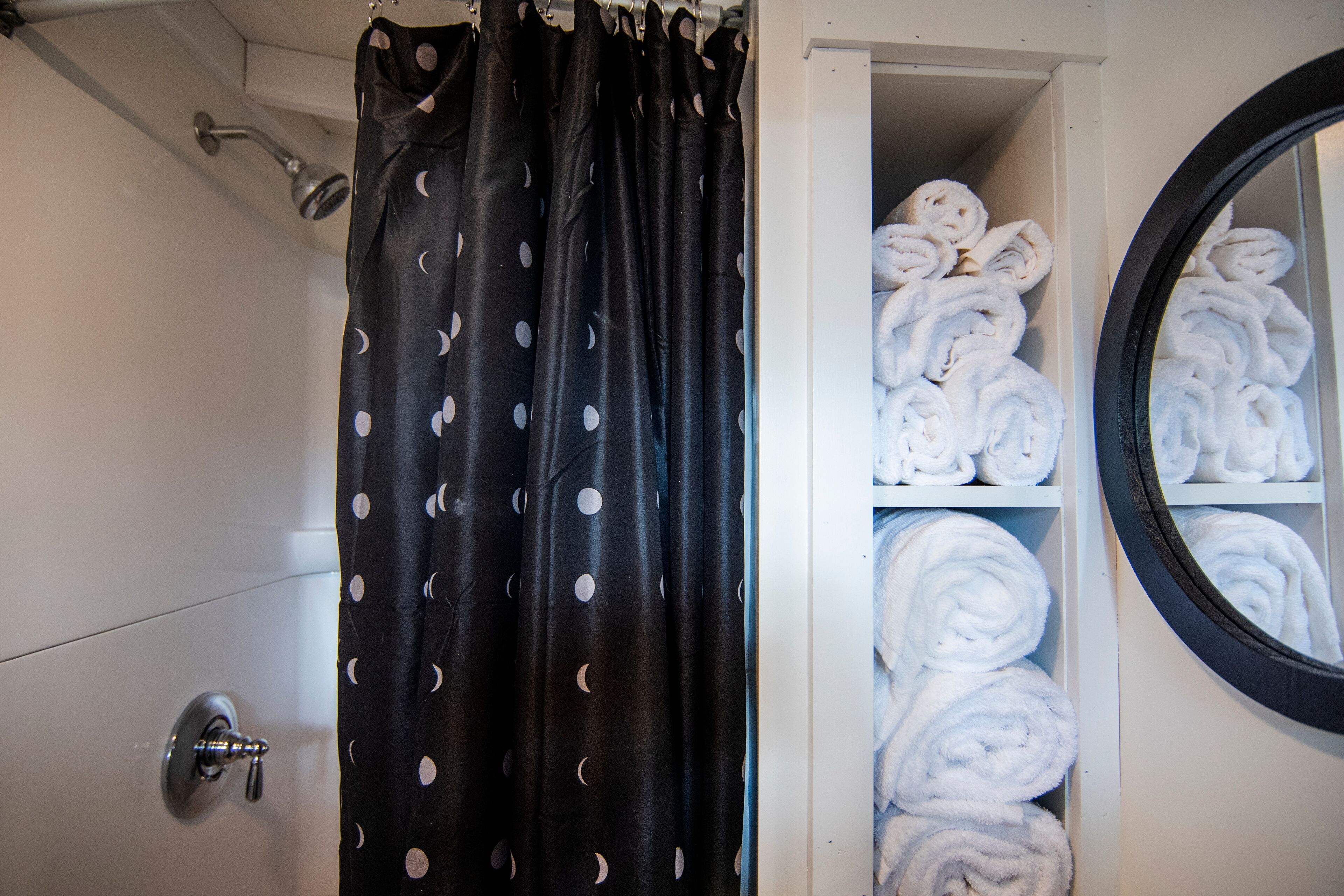 Un baño con cortina de ducha, toallero y espejo.