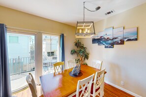 Enjoy meals in this dining area with a table, chairs, and a potted plant, offering a view of the outside from the adjacent balcony.