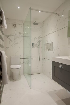 Ein modernes Badezimmer mit einer Duschkabine, einer Toilette und einem Waschtisch mit Spiegel.