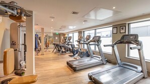 A gym with treadmills, weight machines, and a wooden floor.