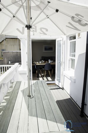 Eine Terrasse im Freien mit Essbereich, einem weißen Sonnenschirm und Blick ins Innere.