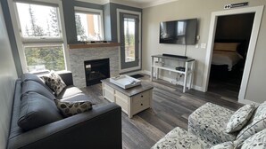 Una sala moderna con chimenea, televisor y sofá.