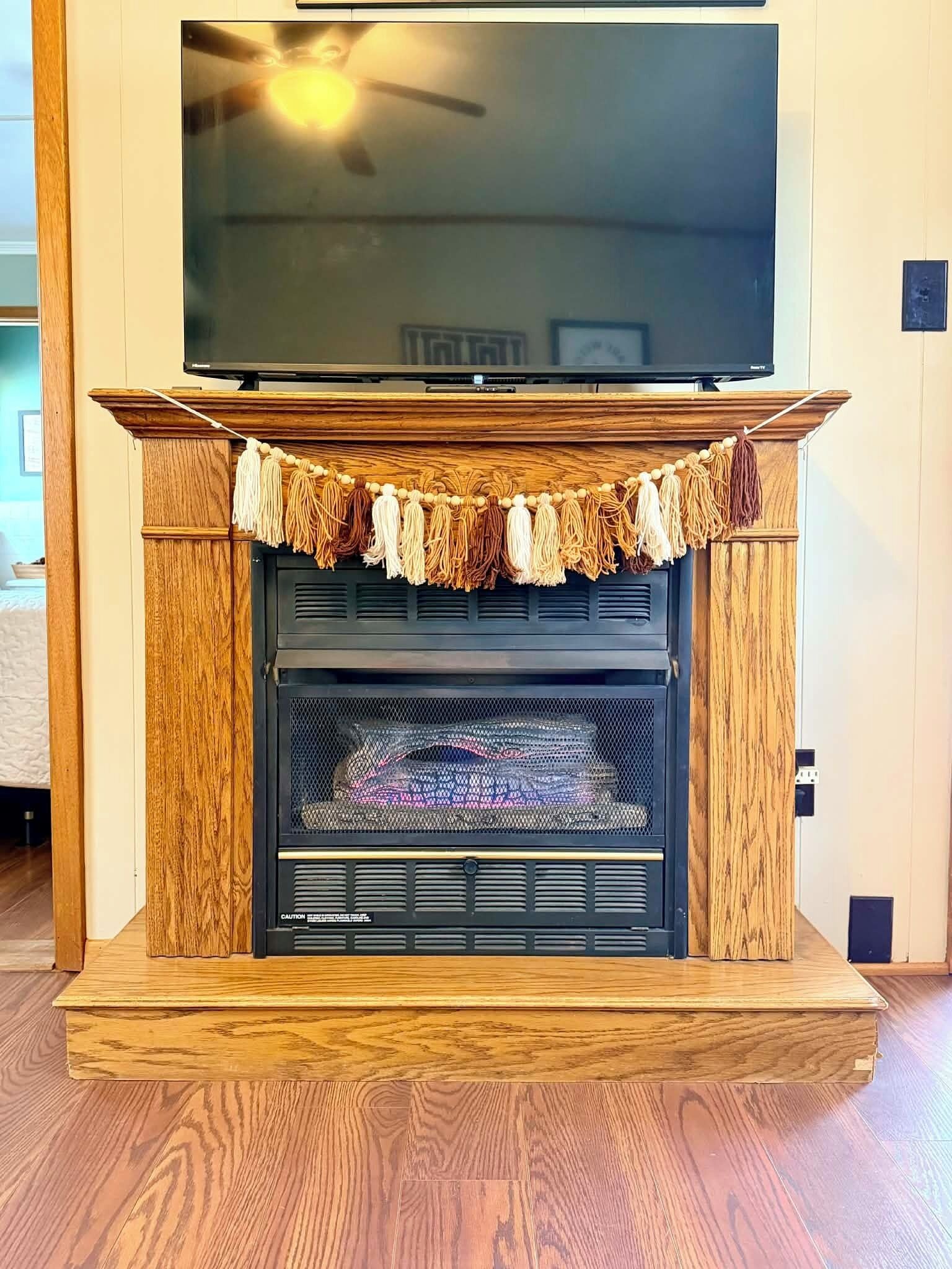 Une cheminée surmontée d’un téléviseur, un ventilateur de plafond et une cheminée en bois.