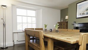 Un coin repas avec une table et des chaises en bois, un radiateur, une lampe sur pied et une cheminée.