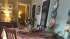 Un comedor con mantel a cuadros, sillas de madera y un florero con flores.