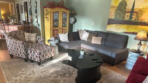 Una sala de estar con sofá, sillones, una mesa de centro y un comedor con mesa y sillas.