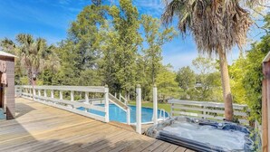 A wooden deck with a hot tub and a pool, surrounded by trees and a white fence. - Gorgeous Colonial House on the Water w/ Pool & Jacuzzi
 (Jacksonville)