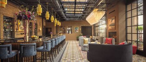 A bar area with a long counter, multiple stools, and a patterned floor.