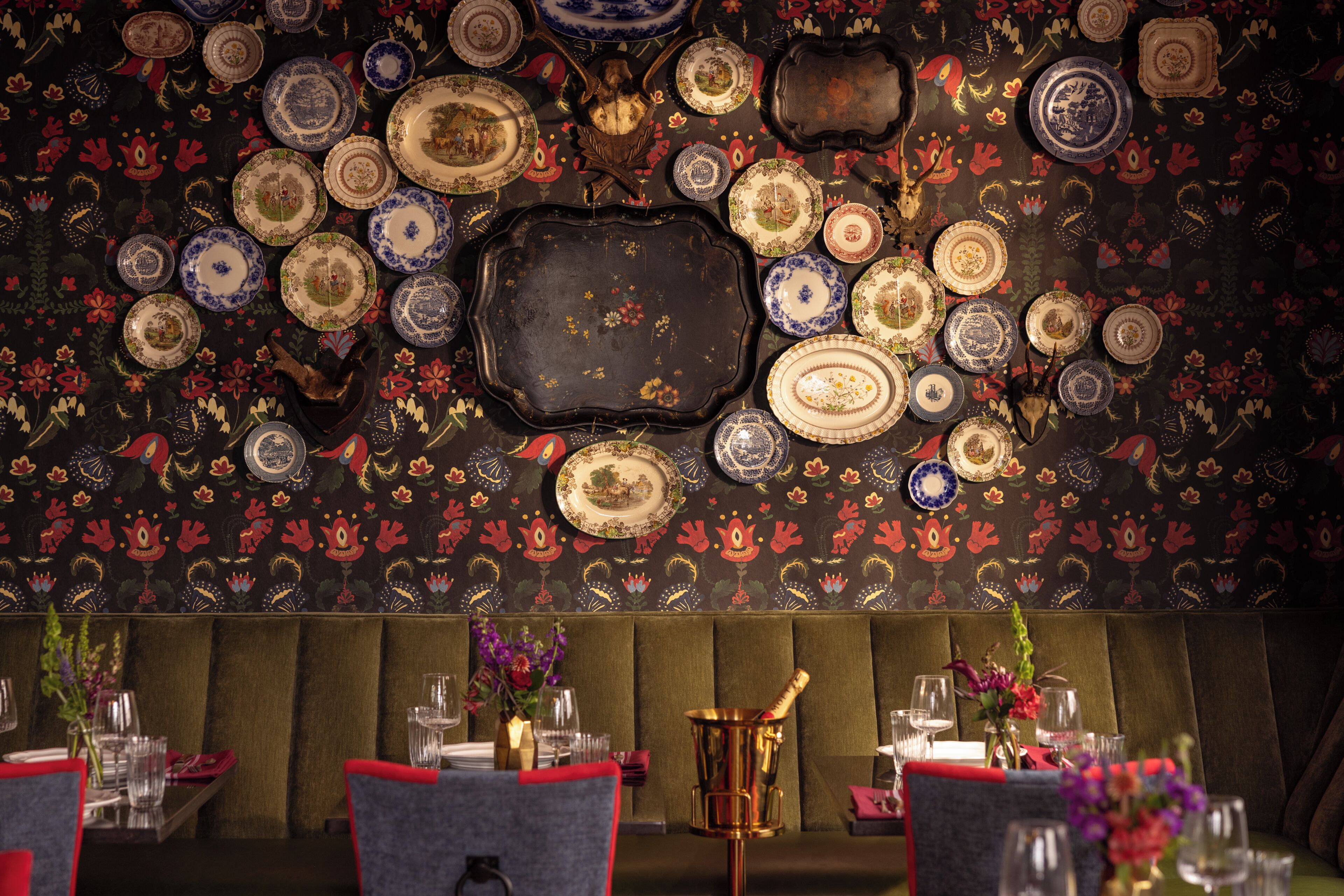 Un restaurant dont un mur est décoré d’assiettes et qui dispose d’un espace salon avec des banquettes rembourrées.