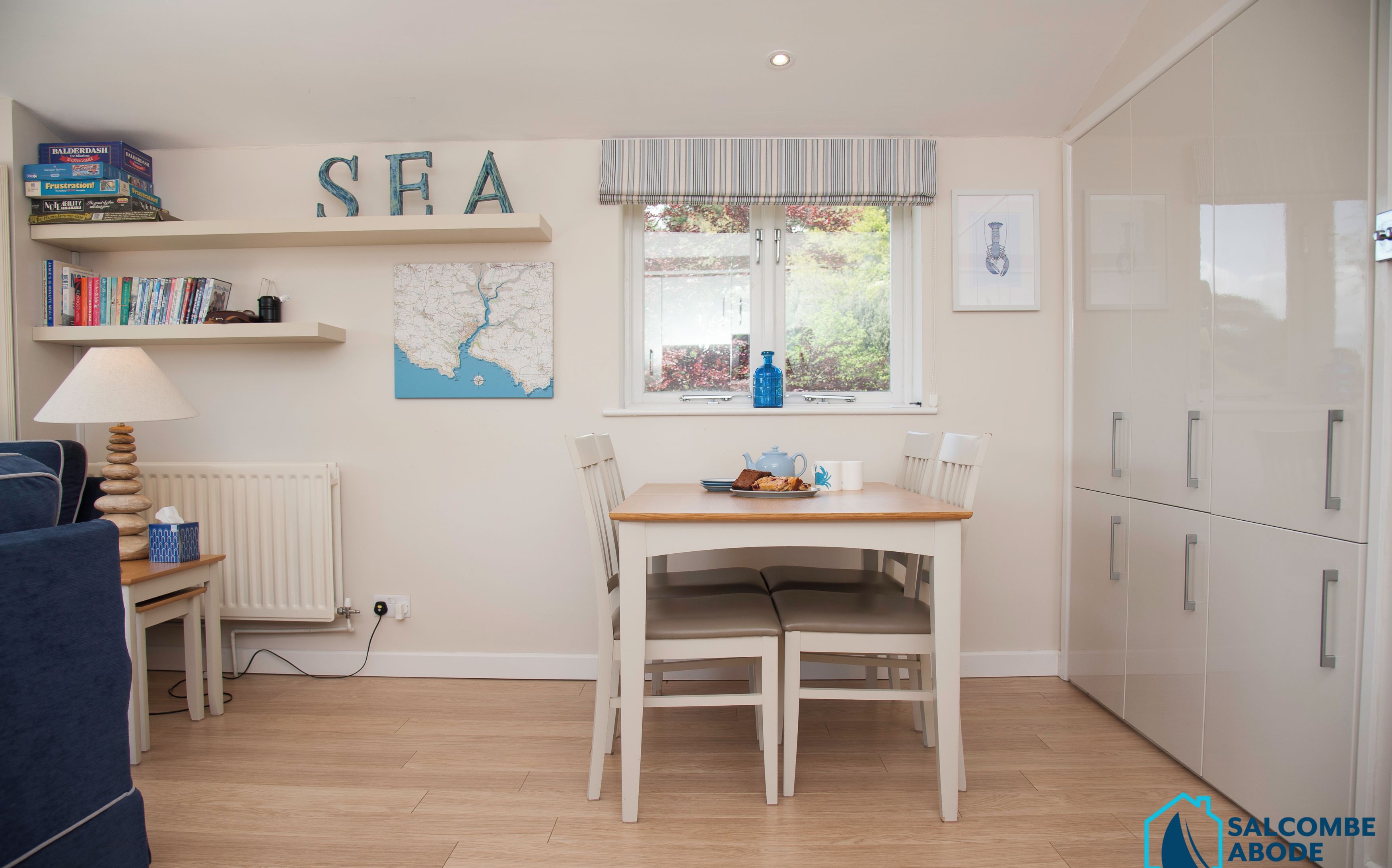 A compact kitchen with a dining table, white cabinets, and a window with a view.