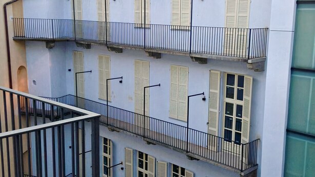 A multi-story building with balconies, a tiled roof, and a light-colored facade. - Eurovision Song Contest downtown Turin (Torino)