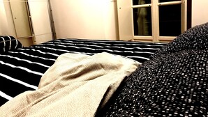 A bed with black and white striped bedding, a white blanket, and a black polka dot cover. - Eurovision Song Contest downtown Turin (Torino)