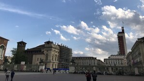 A historic square with classical architecture, including a prominent building with a statue and another with a clock tower. - Eurovision Song Contest downtown Turin (Torino)