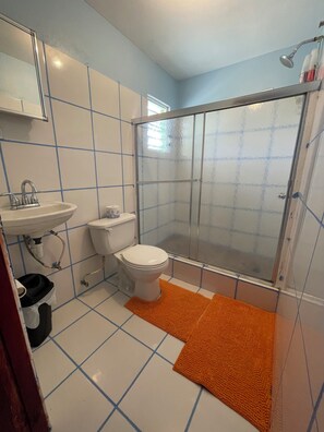 Et badeværelse med vask, toilet og brusebad.