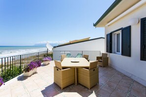 A patio with a table and chairs, overlooking the ocean.