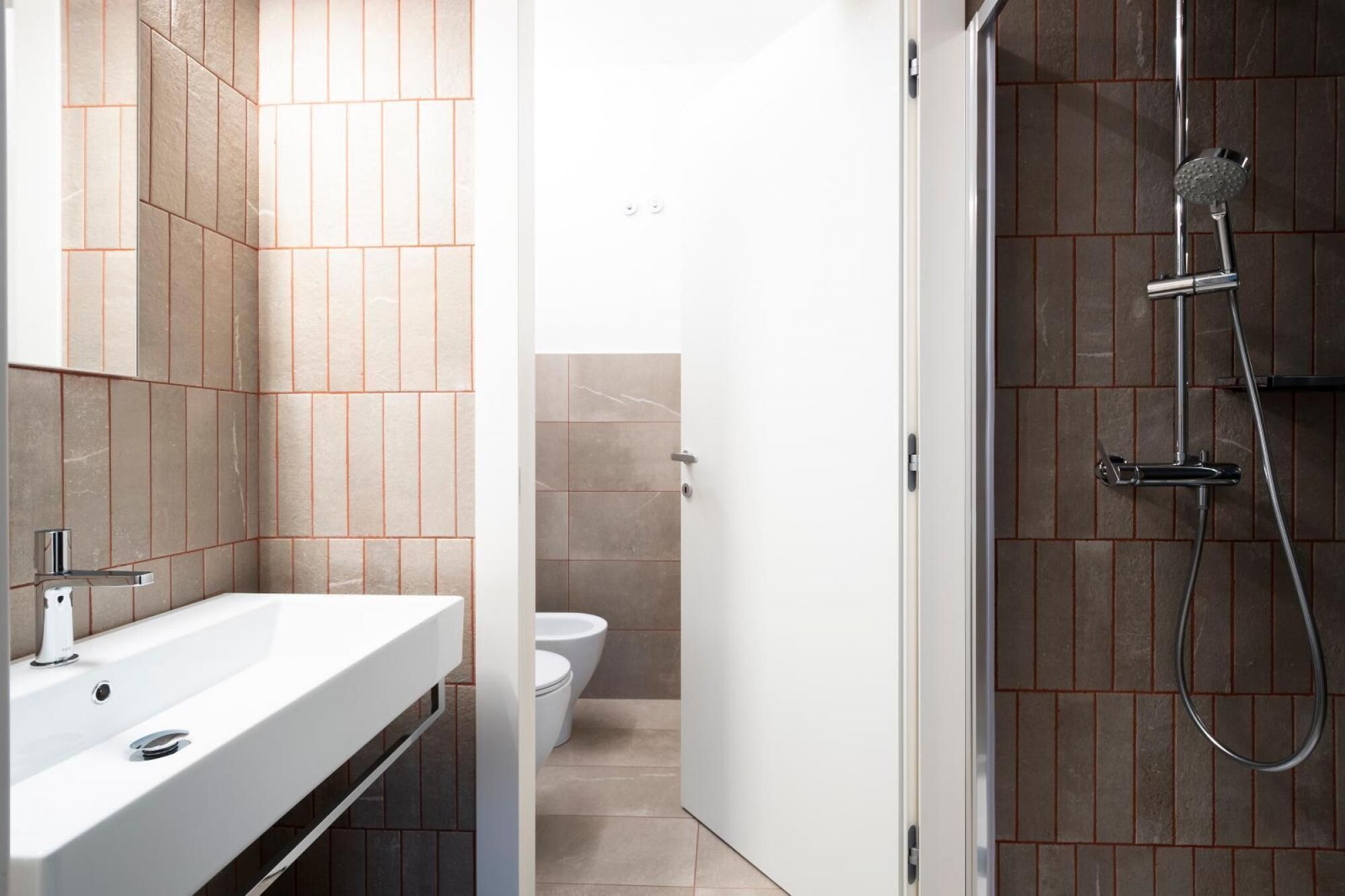 Ein modernes Badezimmer mit einem weißen Waschbecken, einer Toilette und einer Duschkabine.