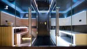 Un sauna moderne avec des murs en verre, des bancs en bois et un espace douche central.