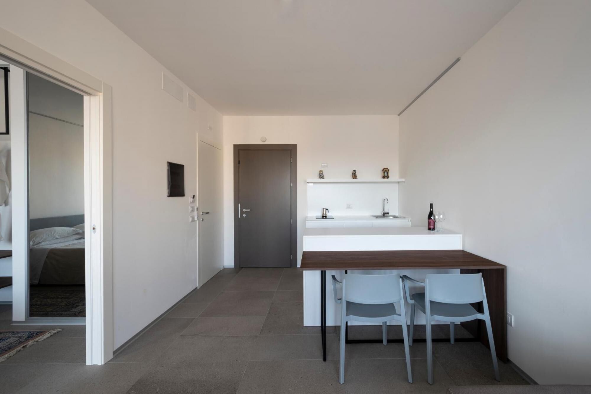 A compact, modern room with a kitchenette, a bed, and a dining area.