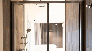 A modern shower area with a glass door, a showerhead, and a control panel. - Alkamuri Posh Hotel Spa 107 Jacuzzi Suite (Alcamo)