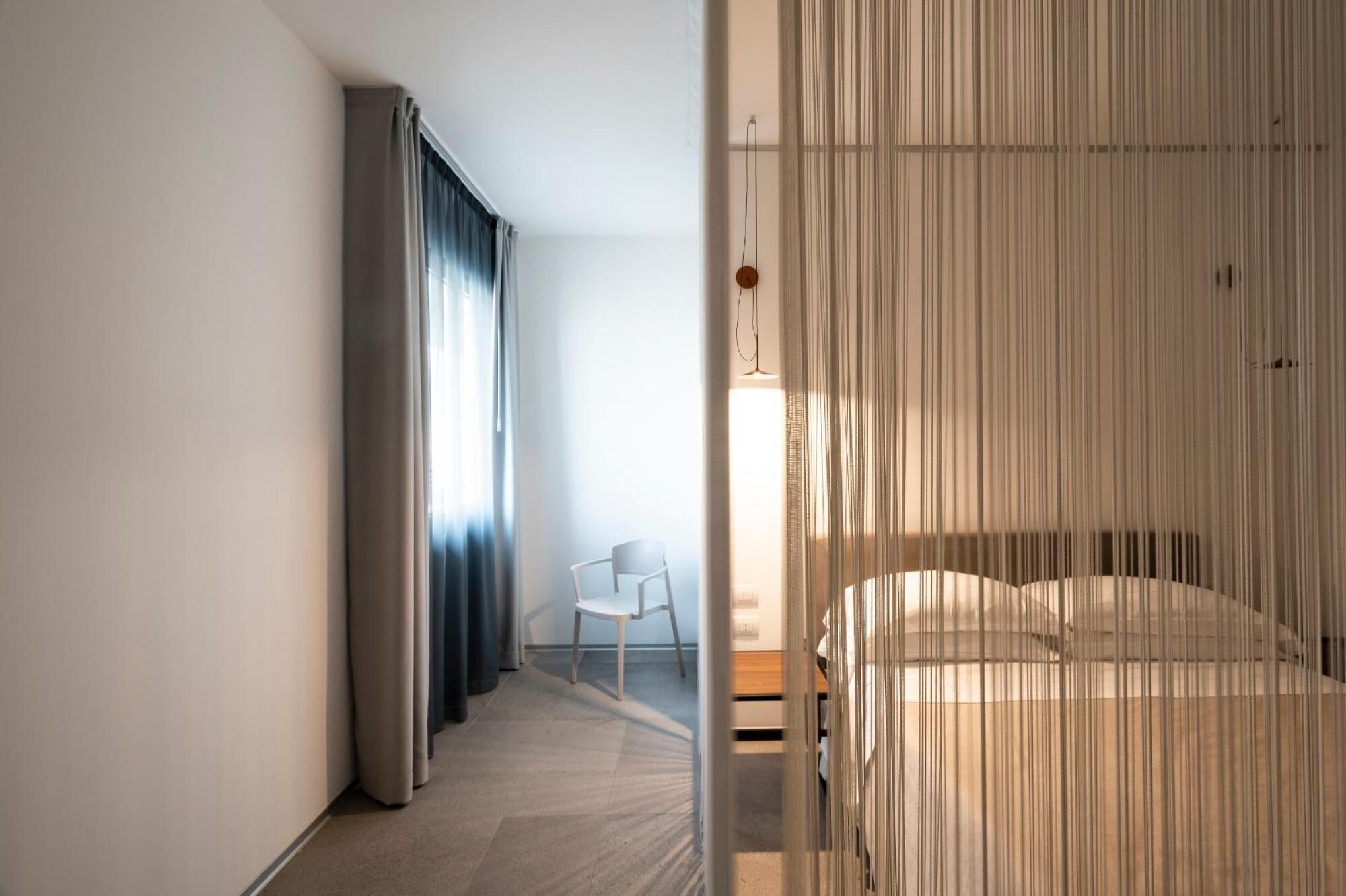 Una habitación de hotel moderna con cama, una silla y vistas al exterior.