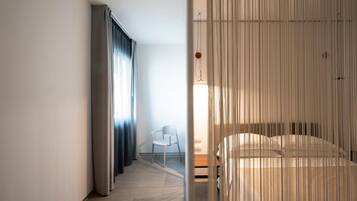 Una habitación de hotel moderna con cama, una silla y vistas al exterior.
