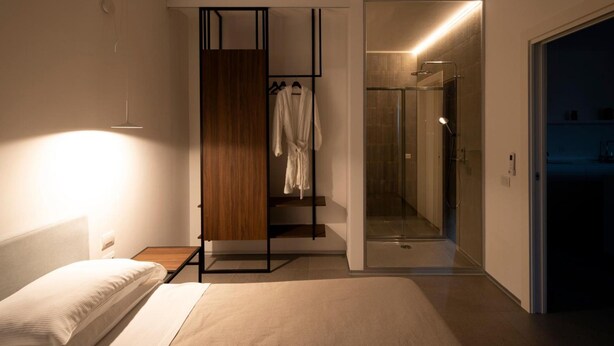 Ein modernes Schlafzimmer mit einem Bett, einem Holzschrank und einer Duschkabine aus Glas.