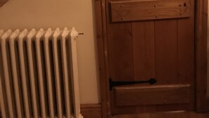 En trädør med en metal lås og en hvid radiator til venstre.