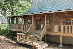 A wooden cabin with a porch, steps, and a sign that reads "Stay While." - The Cabin of Birmingham (Irondale)