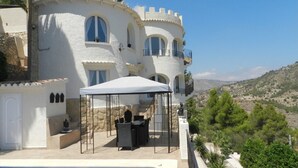 Edifici blanc amb finestres arquejades i un balcó, amb vista a un paisatge amb turons.