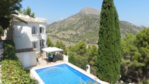 Una vila amb piscina, terrassa coberta i vista a una muntanya.