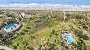 An aerial view of a coastal property with two swimming pools, a beach, and a path leading to the beach. - South Seas Beach Villa 2111 (Captiva)