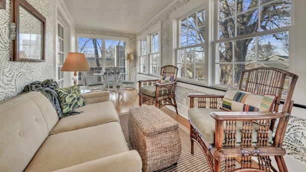 A sunlit room with a sofa, wicker chairs, and a table.
