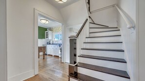 A staircase leading to a kitchen with wooden floors and white cabinetry.