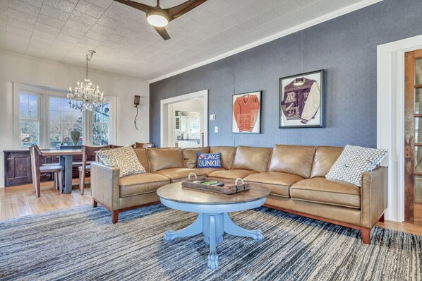 A spacious living room with a large L-shaped sectional sofa, a round coffee table, and a chandelier.