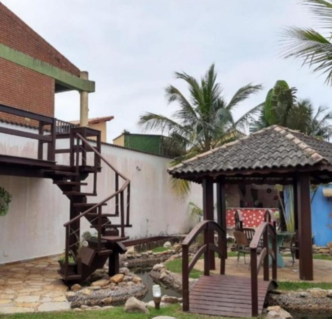 A residential area with a staircase leading to a house, a small gazebo, and a garden with palm trees.