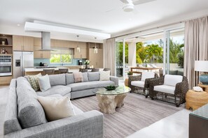 Relax in a spacious living area with a sofa, coffee table, and armchair, and enjoy a balcony with a view of lush greenery.
