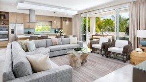 Uma sala de estar moderna com um sofá modular, uma mesa de centro de vidro, cadeiras de vime e vista para o pátio externo.
