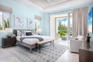 Relax in this serene bedroom with a large bed, bedside tables, and a comfortable bench, offering a peaceful view of the surrounding greenery.