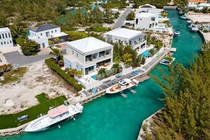 A modern waterfront property with a large house, a boat dock, and a marina.