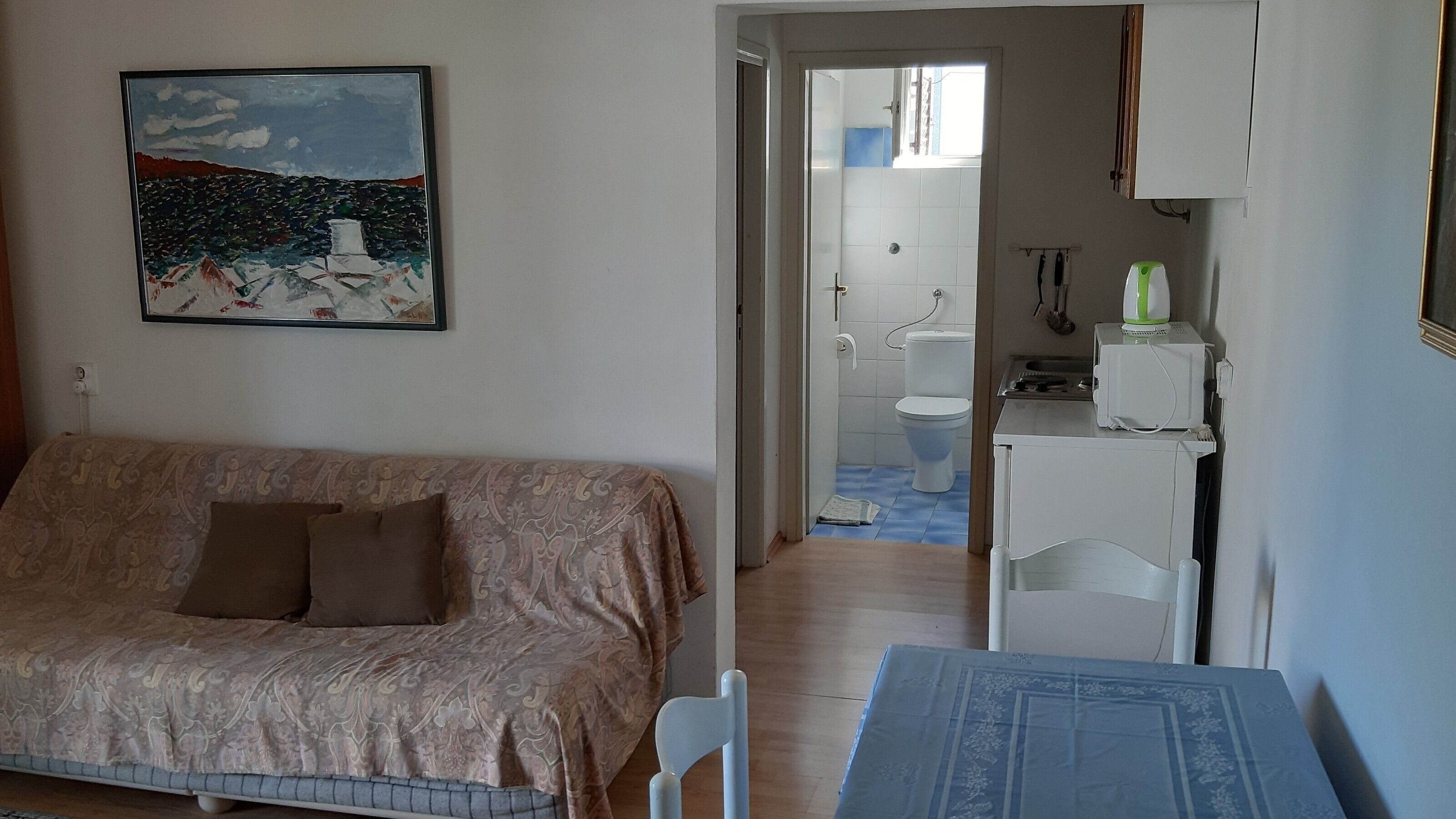 Une chambre à coucher avec un lit, une petite table et un tableau accroché au mur.